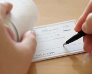 Writing on a check with a pen. 