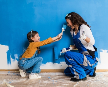 Women and Child holding paint brushes with blue paint. 