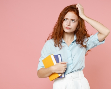 girl with red hair, blue shirt, and white skirt holding books against pink background