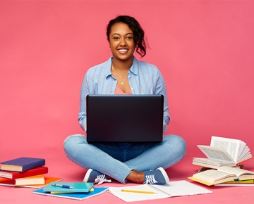young woman on laptop with pink background