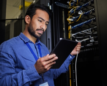 man in blue shirt looking at tablet and server