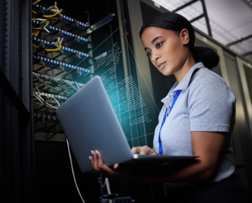 woman looking at laptop with data storage units behind her