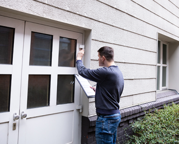 man looking at house with clipboard
