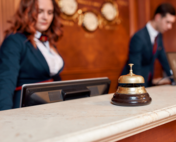 female and male worker behind bell at hotel front desk
