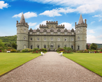 photo of driveway leading to castle with blue sky and clouds