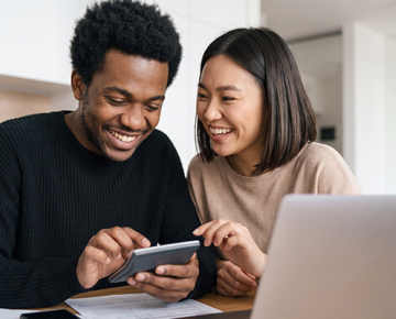 couple looking at calculator and laptop and smiling
