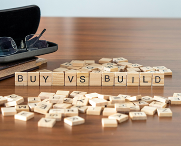 buy vs build scrabble letters on table next to glasses