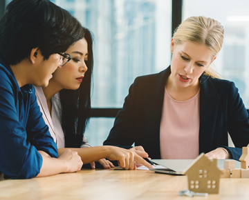 woman reviewing documents with couple with little house model on table