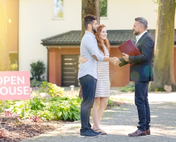 couple with real estate agent outside open house