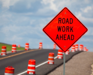 road work ahead sign next to road and orange traffic cones