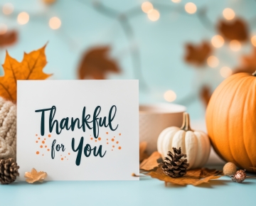 sign that says thankful for you against blue background and pumpkins and leaves