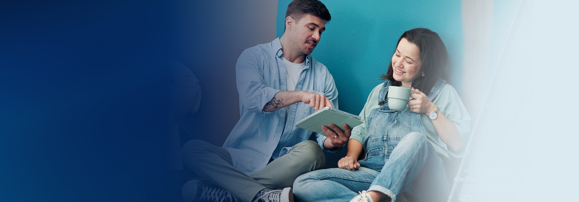 Couple sitting on the floor of a nursery looking at a notebook
