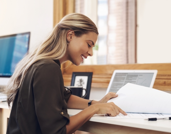 Woman looking through documents at a computer. 