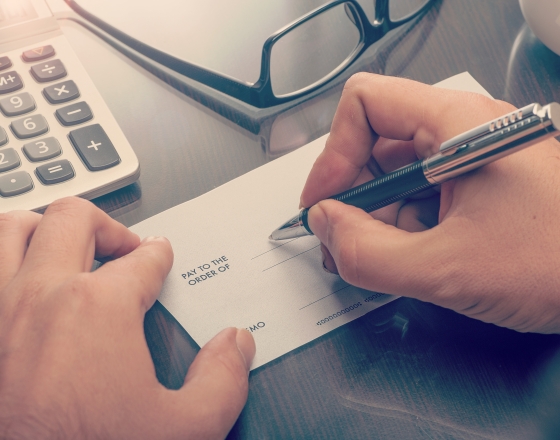 Person writing on check with a pen. 