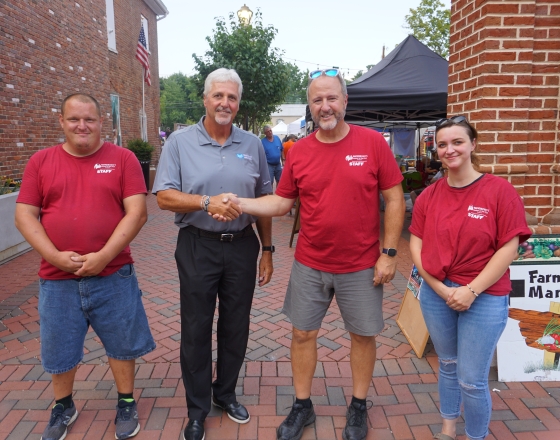 three people in red shirts and one shaking hand of man in gray shirt