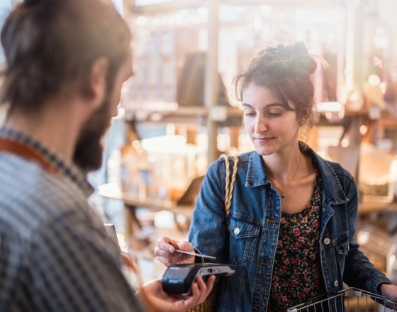 Two people making a store transaction with a tap card. 